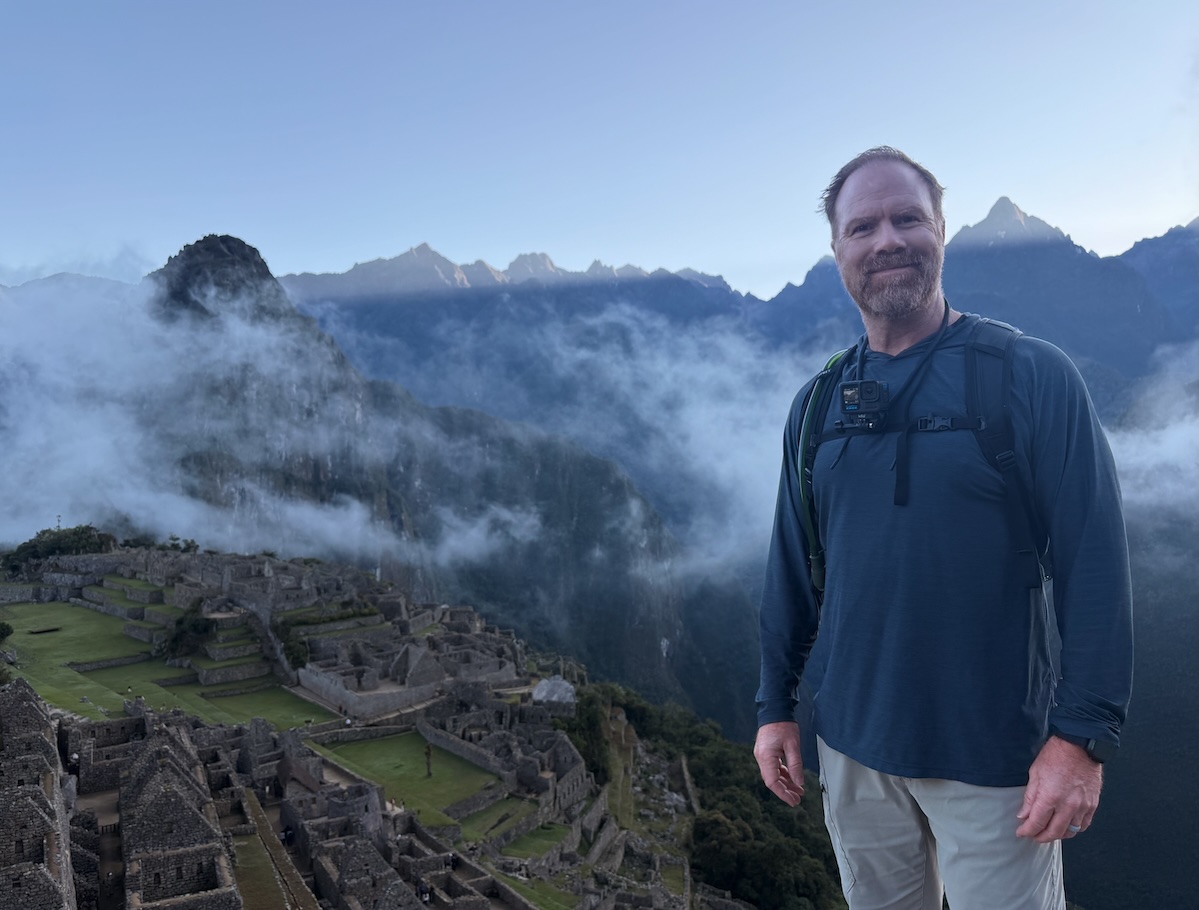 Brian Campbell standing in front of mist-covered mountains and stone ruins